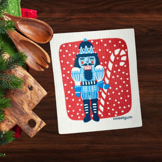 Blue Nutcracker Swedish Dishcloth | Red background with snow
